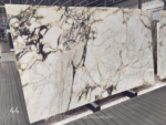 Angled view of Calacatta Viola marble slab with bold plum-grey veining, ivory areas and warm gold details