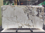 Calacatta Viola marble slab with large ivory fields enclosed by plum-grey and warm gold breccia patterns