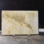 Golden Blue Jade Marble slab with a sweeping taupe band, cream ripples and pale blue-gray patches.