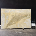 Golden Blue Jade Marble slab showing a diagonal taupe formation framed by golden cream and blue-gray bands.