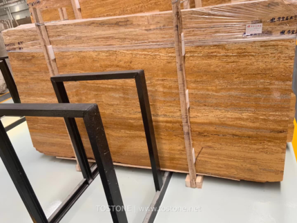 Golden Travertine slabs supported by timber braces in a warehouse