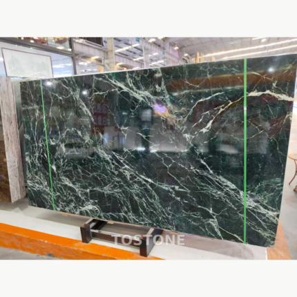 Angled view of a Greek Verde Alpi marble slab showing white vein networks across a deep forest-green surface.