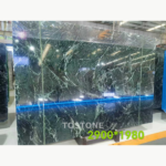 Dark green Greek Verde Alpi marble slab with sweeping pale veins, shown at an angle with existing image markings.