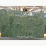 Indian Large Flower Green Marble slab suspended indoors, showing broad green areas and fine dark web-like lines
