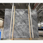 Italian Space Grey Marble slab held by lifting straps, showing cloudy white areas across a charcoal-grey background.