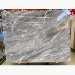 Italian Space Grey Marble slab with sweeping grey bands crossed by slender bright white veins in a showroom.