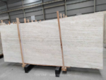Italian Super White Travertine Vein Cut slabs held by timber braces in a warehouse