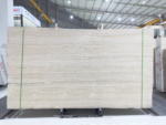 Italian Super White Travertine Vein Cut slabs secured by green straps with fine cream banding