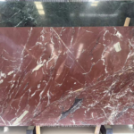 Kadiya Red Marble slab with a burgundy background, white branching veins and a dark gray accent