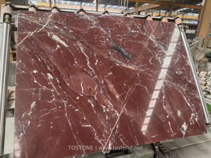 Angled workshop view of Kadiya Red Marble slab showing cream and white veining