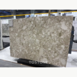 Montage Marble slab with irregular ivory and cream shapes across a taupe background in a showroom