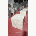 Foreground Montage Marble cube-form piece with cream and ivory patterning in a stone workshop