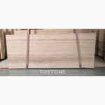 Wide Pakistan travertine slab with soft ivory streaks and gently rippled beige banding between lifting straps.