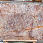 Phoenix Red Marble slab with a gray-blush background, branching burgundy veins and broad golden-ochre lines
