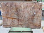 Wide Phoenix Red Marble slab with intersecting burgundy and ochre veins in a warehouse