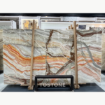 Rainbow Agate Marble in a timber rack, with grey and cream layers, orange waves and dark brown branching accents.