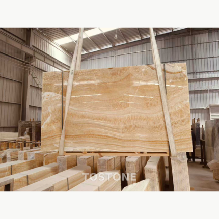 Rosin Jade Marble slab held by lifting straps, showing warm amber and cream horizontal waves.