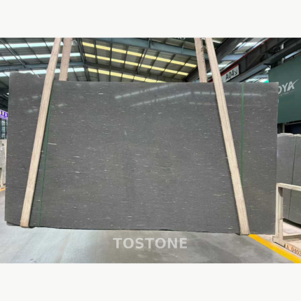 Sandalwood Snow Marble slab held by lifting straps, with a charcoal-grey base and fine horizontal pale streaks.