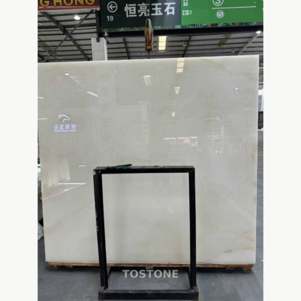 Snow White Marble slab with a milky white surface and faint warm accents, displayed behind a black support frame.