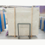 Sofitel Gold Marble slab with a pale cream field and sparse fine veins behind a central metal support.