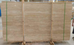 Turkish cream travertine slabs secured with wooden supports and green straps, showing beige horizontal layers
