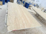 Lengthwise workshop view of a Turkish cream travertine slab with pale cream and beige linear patterning