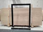 Cream and beige Turkish travertine slabs standing on display racks in a stone workshop