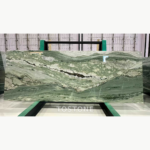 Victoria Green Marble slab with a sweeping sage-green pattern, irregular white areas and a dark central vein.