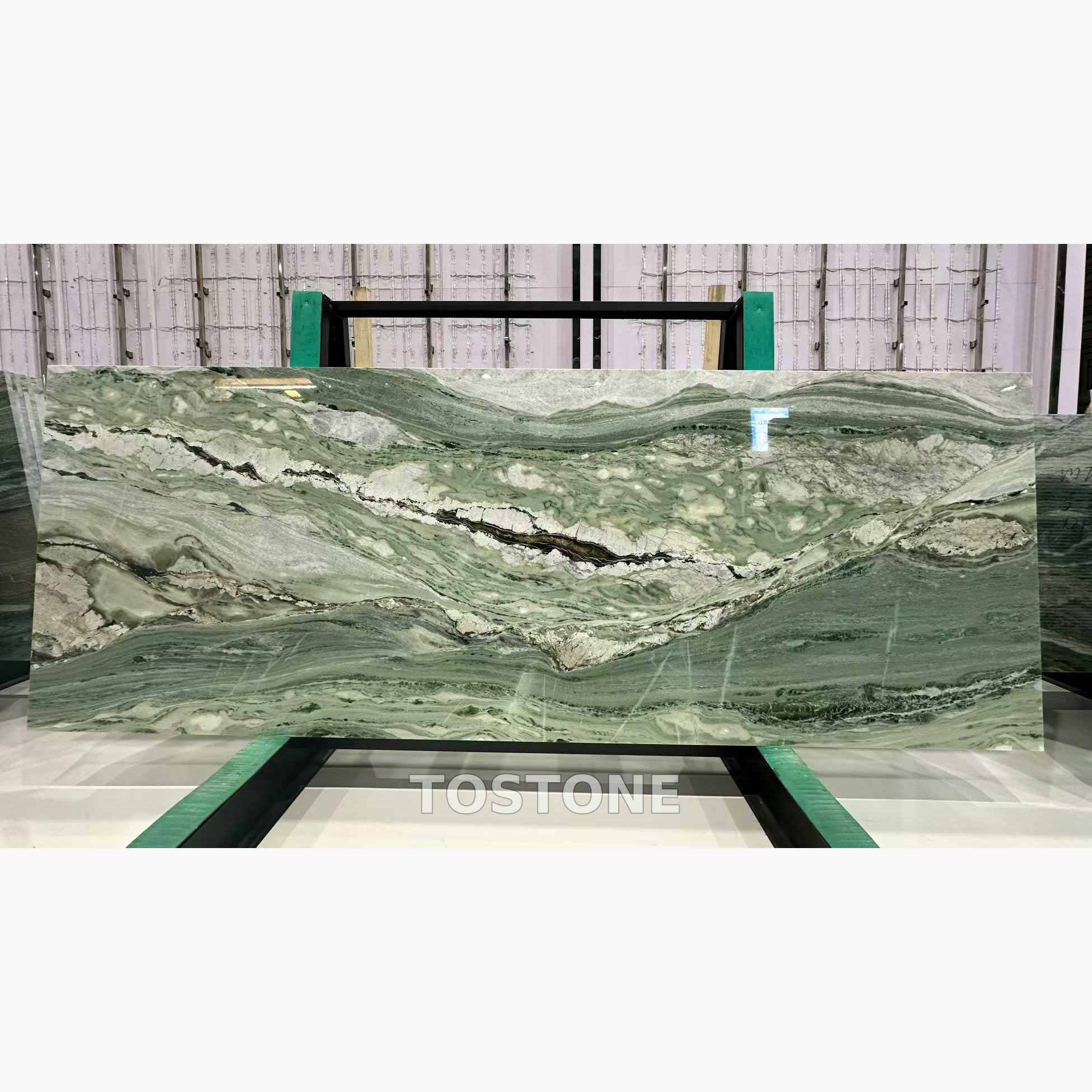 victoria-green-marble-01-square-review Victoria Green Marble slab with a sweeping sage-green pattern, irregular white areas and a dark central vein.