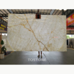 White Crystal Marble slab with an ivory-white background, layered pale veining and a bold gold-brown diagonal vein.