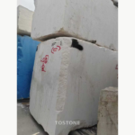 Stacked White Mushroom Marble blocks with pale faces, rough edges and scattered gray markings.