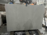 White Travertine Slab on workshop supports beneath a lifting clamp