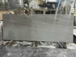 Wide White Travertine Slab showing flowing pale gray bands in a workshop