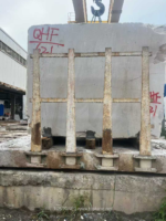 White Travertine stone block held in a support frame in a stone yard