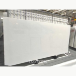 Angled view of a Ya Shi White Jade Marble slab with gentle white clouding and sparse grey markings